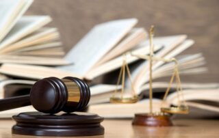 Age of Consent Laws in Ottawa, Ontario, Canada portrayed by a gavel, scales of justice and open legal texts on the wooden table.