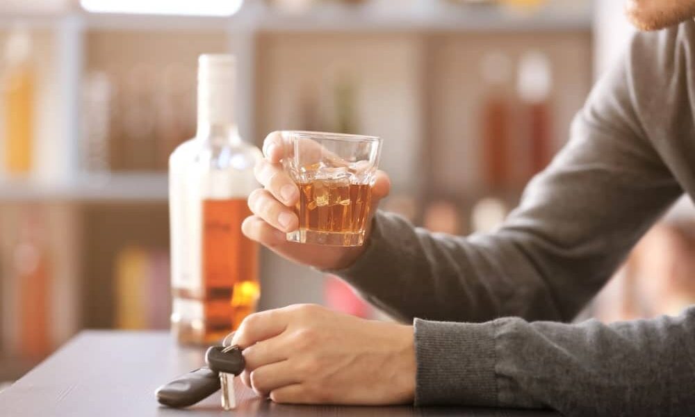 Over 80 rule in Ontario means it's illegal to operate any motor vehicle with blood alcohol concentration over 80 milligrams of alcohol per 100 milliliters of blood. The image portrays a man with a whiskey glass and car keys.